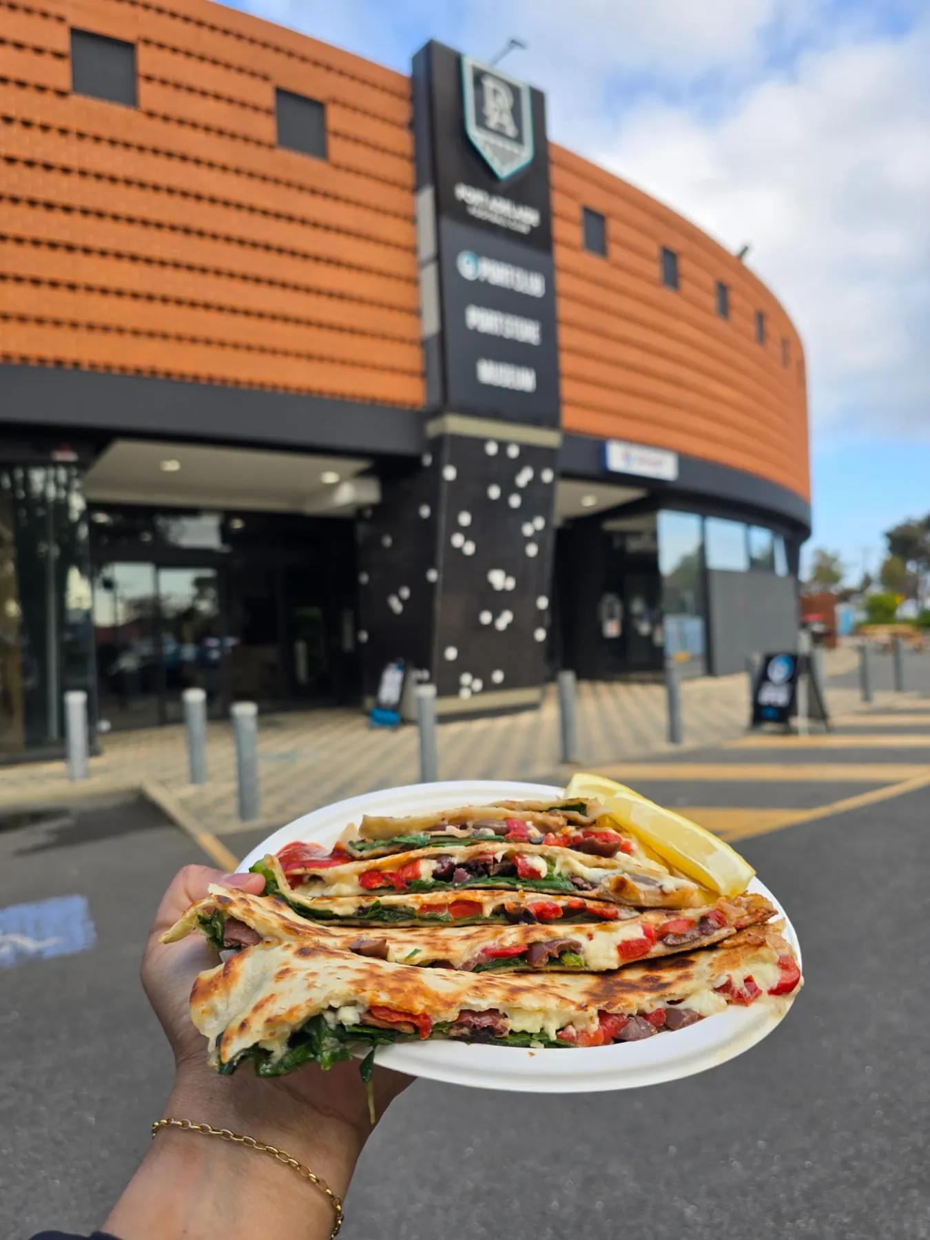 A plate of veggie gözleme with lemon held up outside a venue in Adelaide