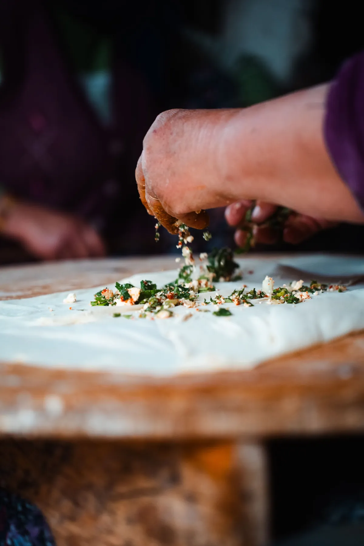 Traditional gözleme filling spread by hand over freshly rolled dough