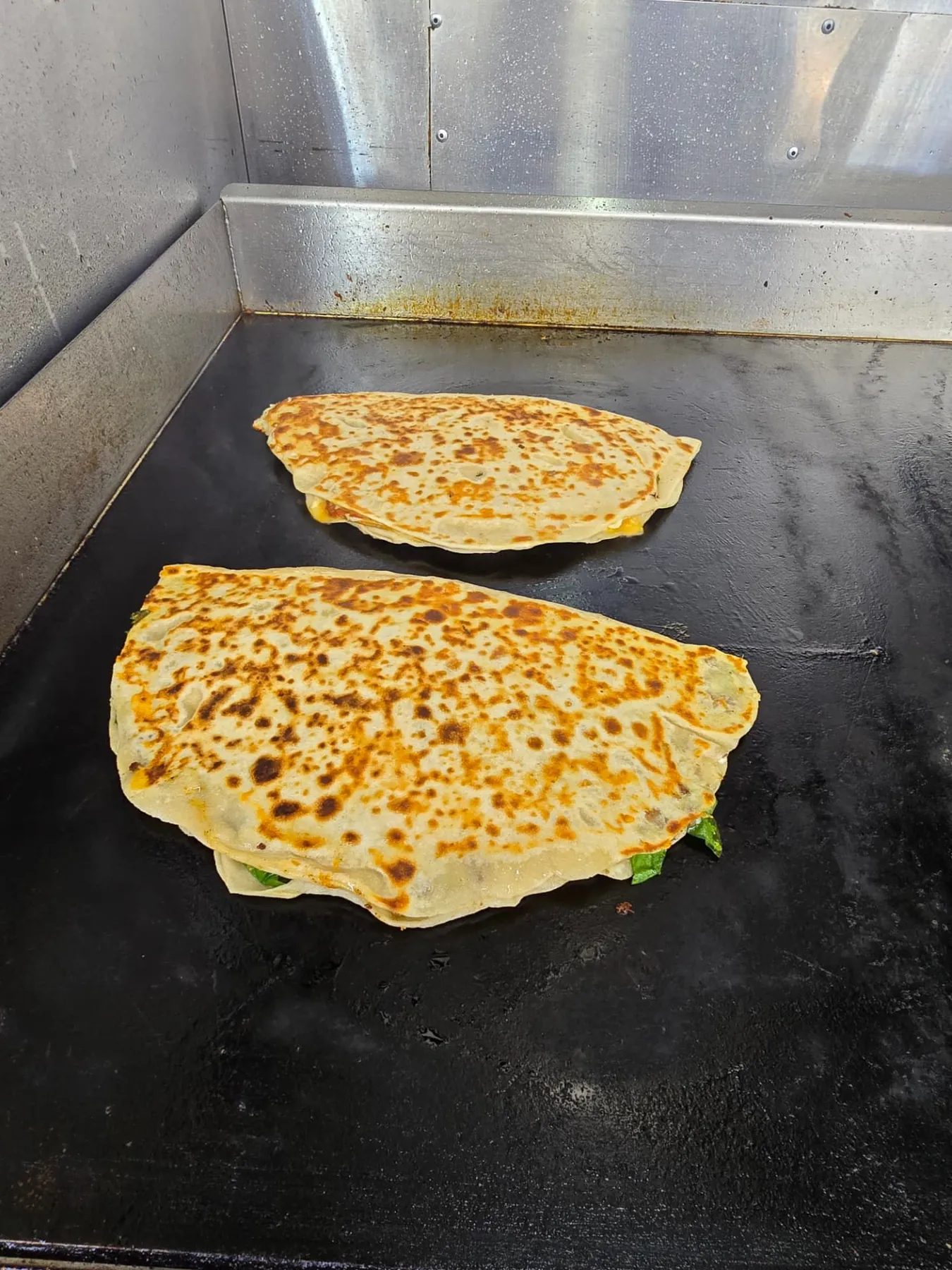 Two gözleme blistering on the hot griddle inside the truck
