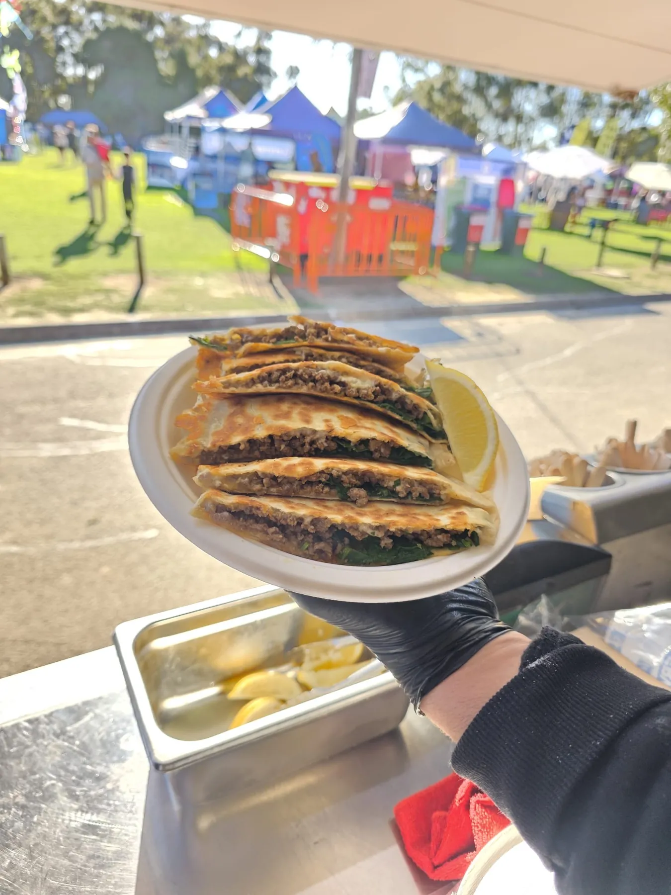 Plate of spiced beef and spinach gözleme wedges with a lemon wedge, handed out of the truck window